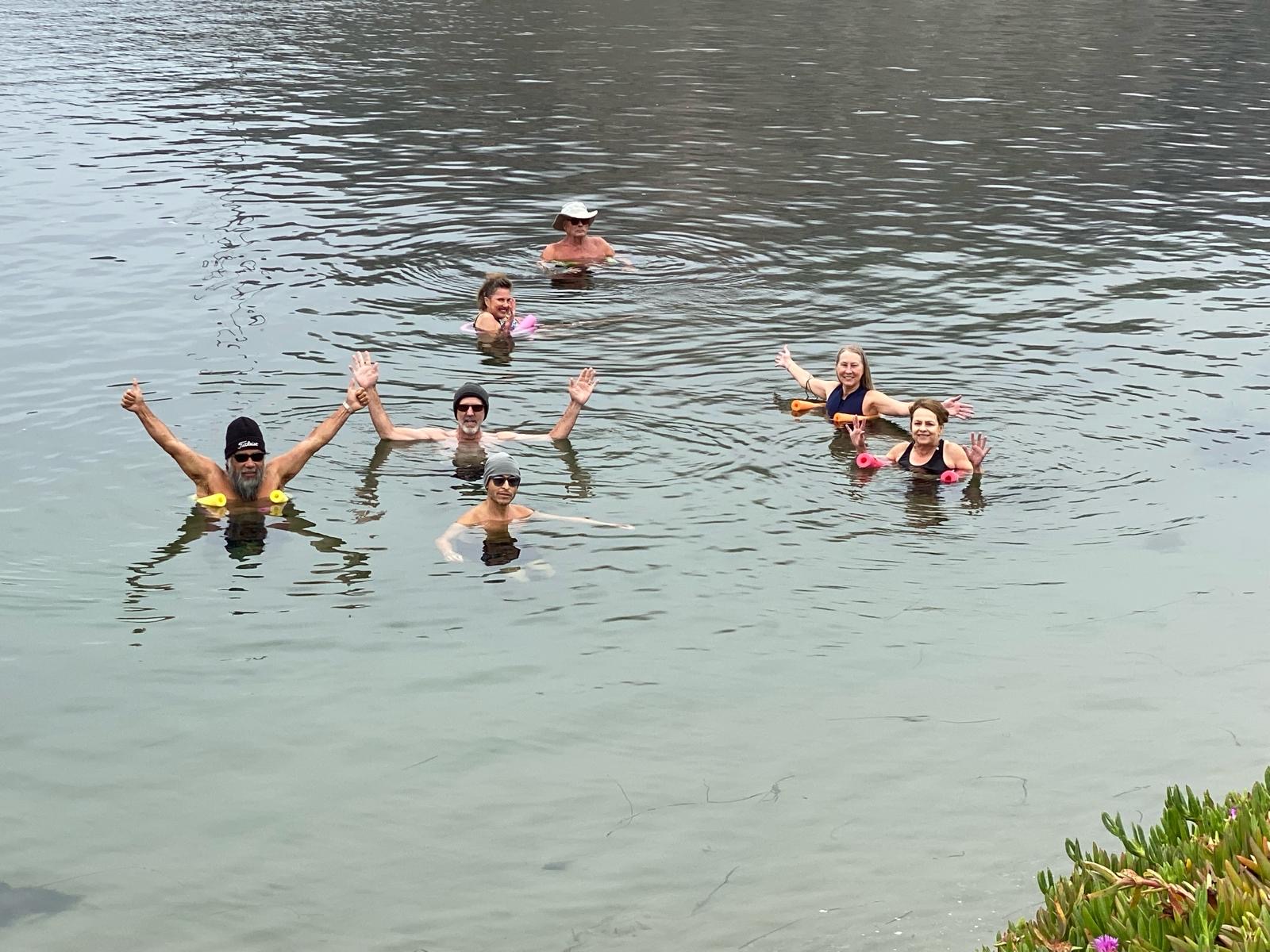 Club members with arms raised, laughing together in chest-deep water