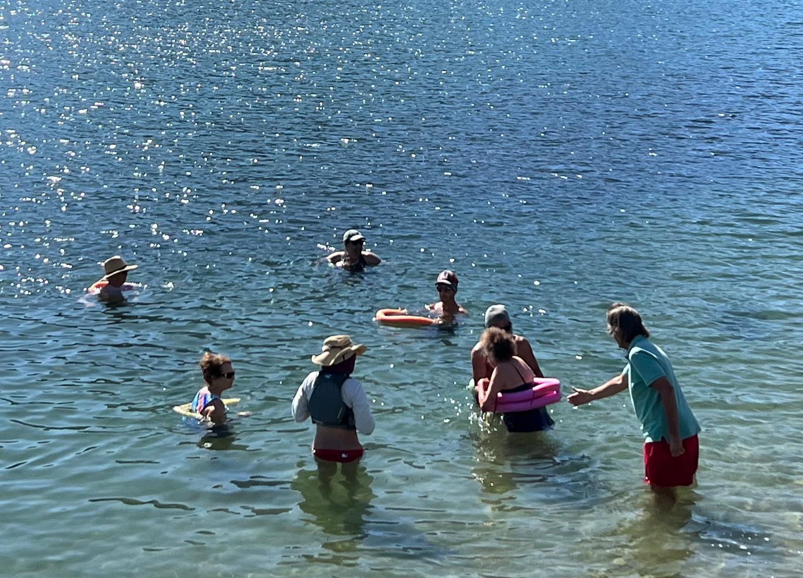 Swimmers with pool noodles floating in sparkling blue water